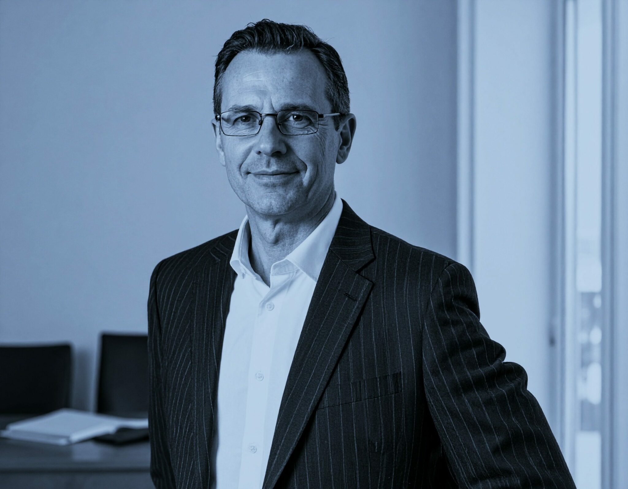 Portrait d’un homme en costume dans un bureau lumineux, regard confiant — image représentant un professionnel expérimenté, symbole de leadership et d’engagement RH.