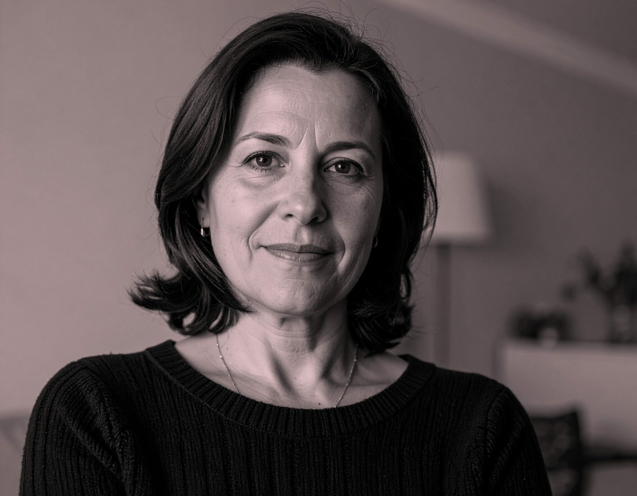 Portrait d’une femme mûre au regard calme, dans un intérieur sobre — image illustrant l’écoute, l’expérience et l’accompagnement bienveillant.