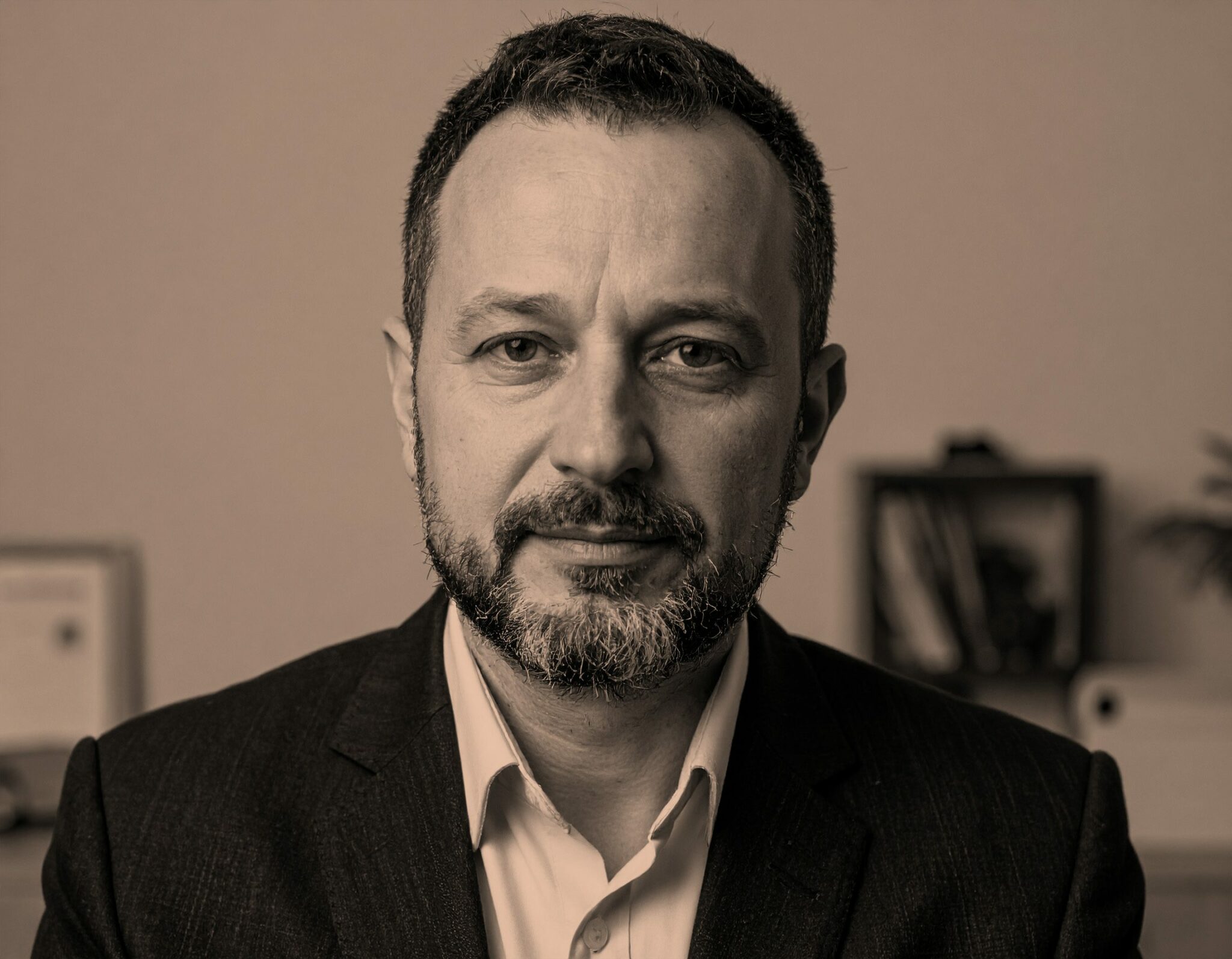 Portrait d’un homme en costume assis dans un bureau, regard direct et posé — image incarnant l’expertise, la crédibilité et l’engagement professionnel.
